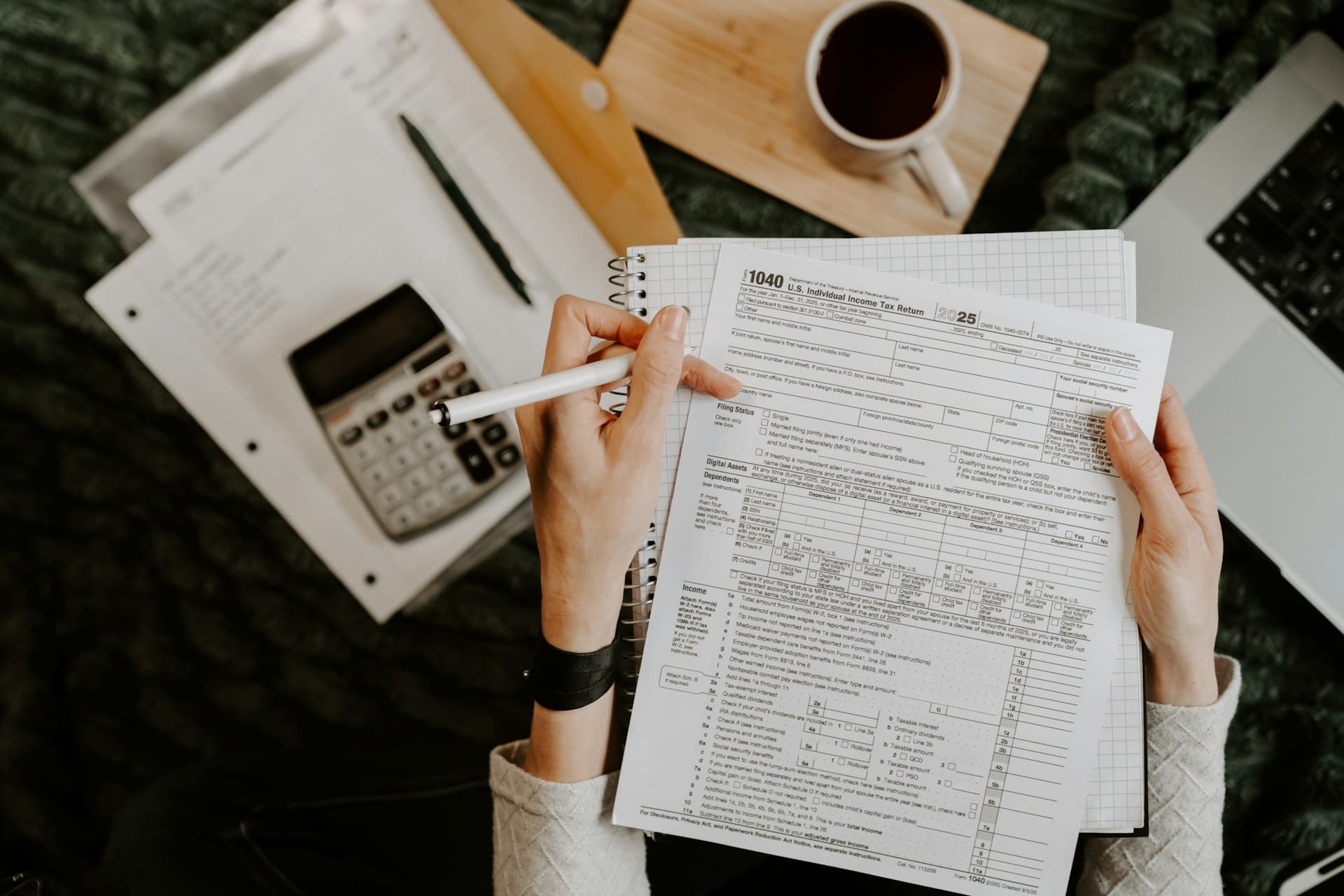 Person reviewing tax forms with a calculator and laptop for multi-year tax filing support.