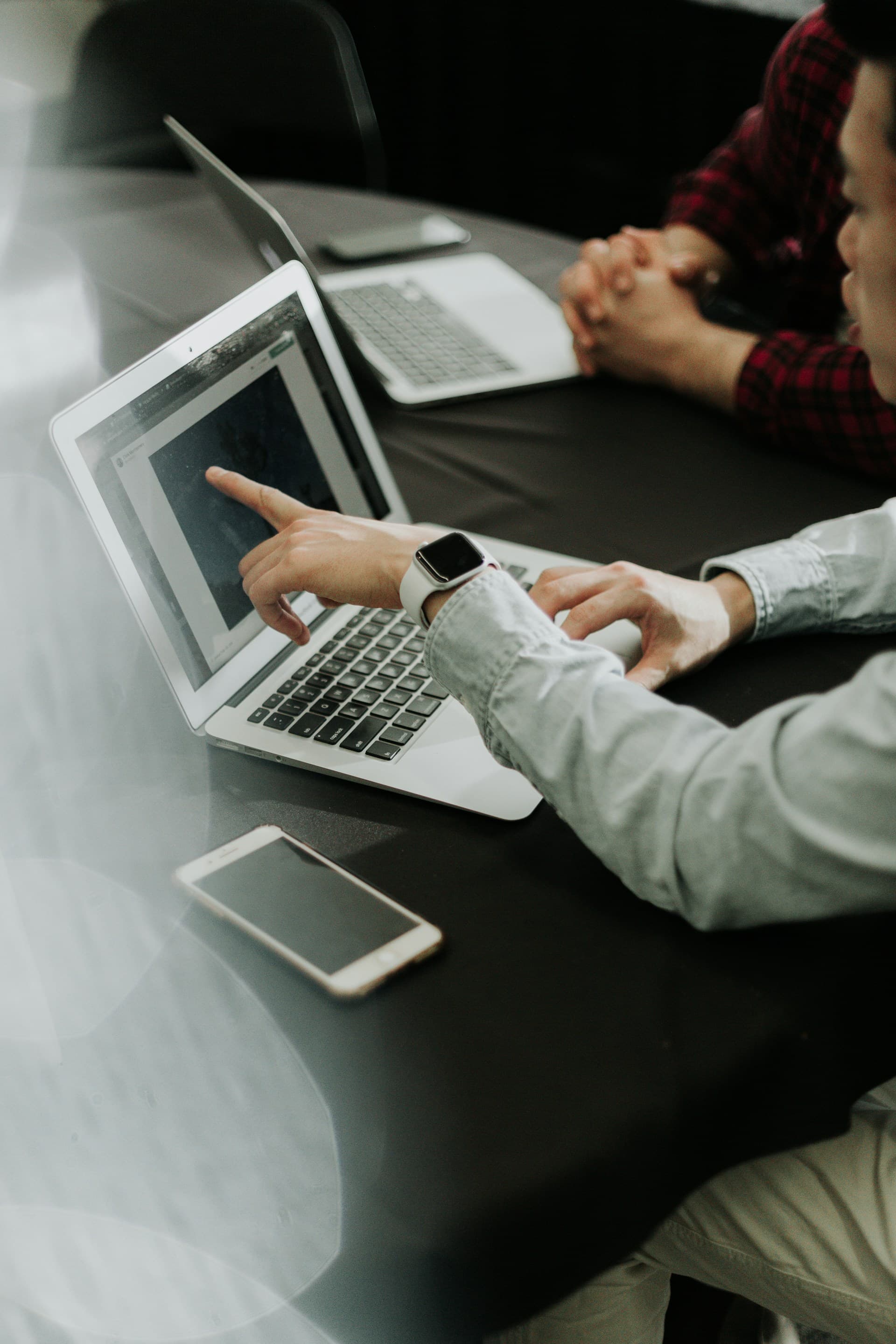 Two people sitting at a table with laptops for tax consulting and financial planning.